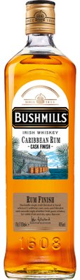 Eine Flasche Bushmills Irish Whiskey mit goldener Kappe und einem Etikett, das die Karibik und Fässer zeigt.