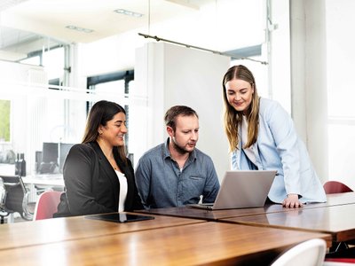 Drei Kollegen diskutieren über ein Projekt am Laptop